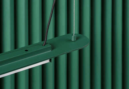 Dark green metal lamp hanging on folded colorful wall background in studioの写真素材