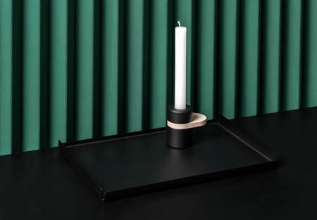 Trendy metal black tray with dark candlestick on folded green wall backgroundの写真素材