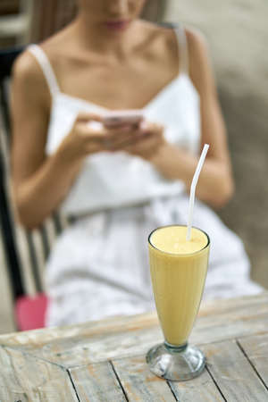Woman using her smartphone in outdoor restaurant on tropical beachの写真素材