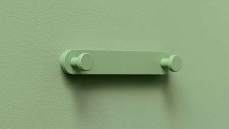 Trendy metal green hanger on the same color textured wall indoors. Closeup horizontal photo.の写真素材