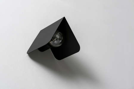 Trendy metal black lamp with an edison light bulb on the textured gray wall indoors. Closeup horizontal photo.の写真素材