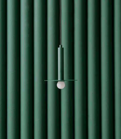 Trendy metal dark green lamp is hanging on the same color folded wall background indoors. Closeup vertical photo.の写真素材