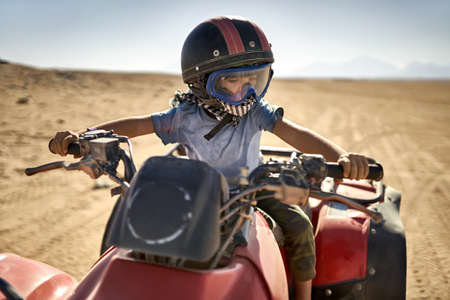 Kid in helmet and protect mask riding quad bikeの写真素材