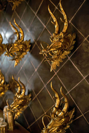 Several gold dragon heads on tiled wall indoorsの写真素材