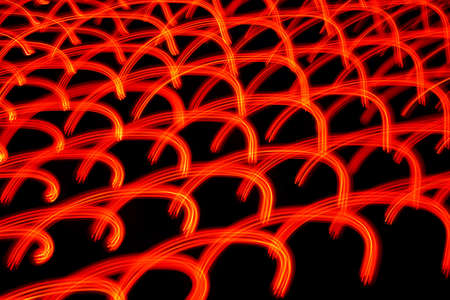 Rounded red-orange glowing patterns in motion on the dark background. Closeup horizontal photo.の写真素材