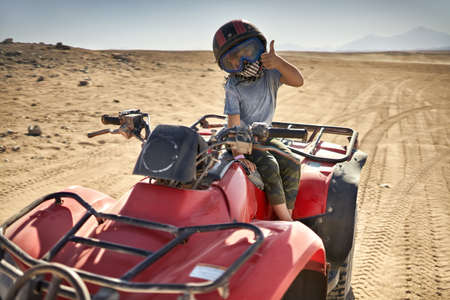 Kid in helmet and protect mask riding quad bikeの写真素材