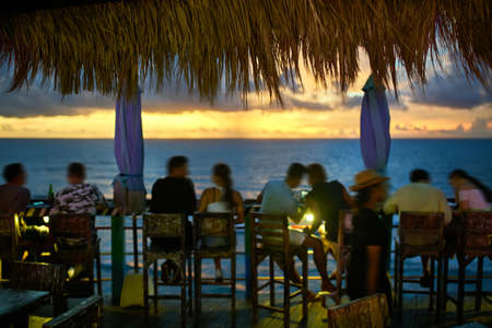 Outdoor restaurant in balinese style on sunset sea backgroundの写真素材