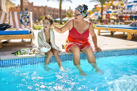 Old lady with her grandson relaxing near pool on resortの写真素材