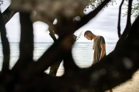 Handsome guy stands on tropical sand beachの写真素材