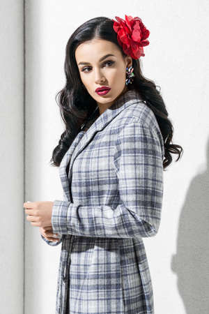 Brunette model in stylish coat and accessories posing in studioの写真素材
