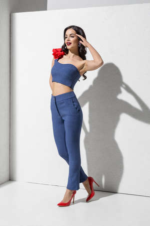 Brunette model in colorful clothing and accessories posing in studioの写真素材