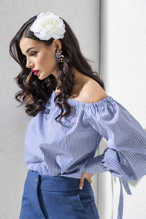 Brunette model in stylish clothing and accessories posing in studioの写真素材