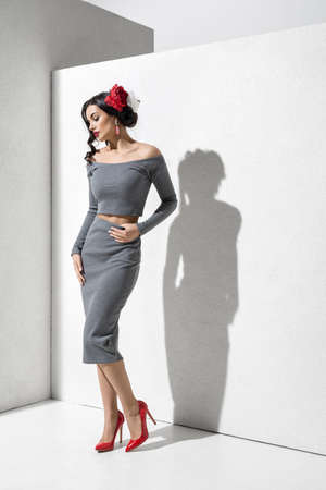 Brunette model in stylish clothing and accessories posing in studioの写真素材