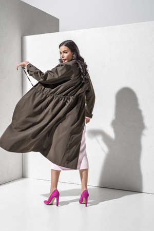 Brunette model in stylish clothing and accessories posing in studioの写真素材
