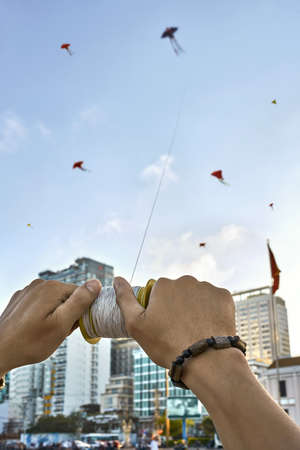Guy launching colorful kite up into sky on city streetの写真素材