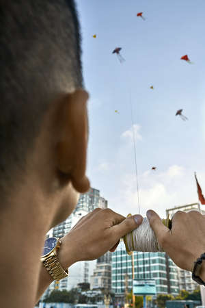 Guy launching colorful kite up into sky on city streetの写真素材