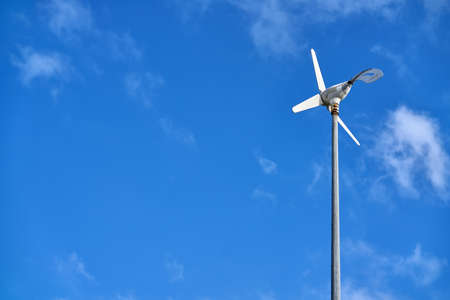 Sun is shining onto wind generator on blue sky backgroundの写真素材