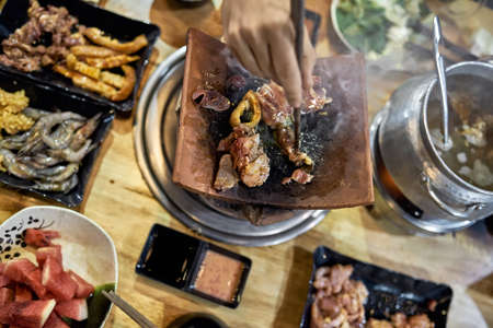 Visitor of traditional vietnamese restaurant cooking meat on hot potの写真素材