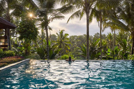 Woman in white swimsuit in outdoor pool on green jungle backgroundの写真素材