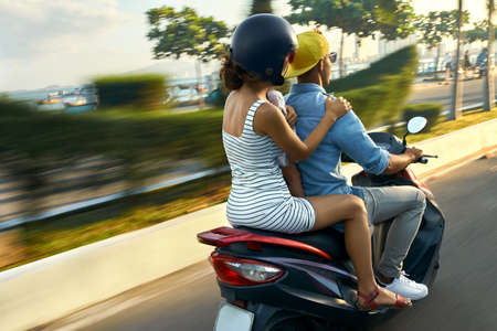 Parents with their child riding motorcycle on sunny city streetの写真素材