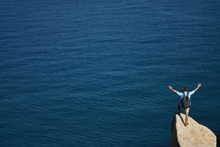 Traveler posing on stone on rocky seashore outdoors