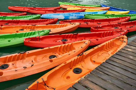 Multicolored canoes moored to wooden pier on nature backgroundの写真素材