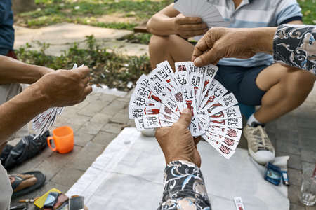 Asian gamers playing cards in park outdoorsの写真素材