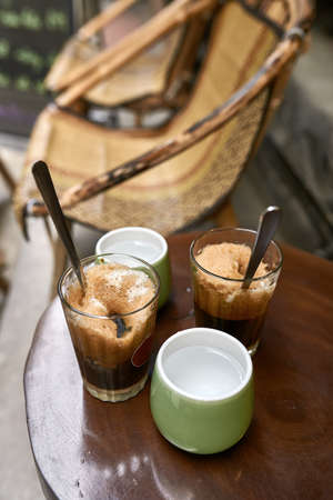 Refreshing iced coffee drinks and cups with water on round table outdoorsの写真素材