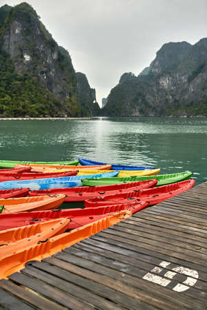 Multicolored canoes moored to wooden pier on nature backgroundの写真素材