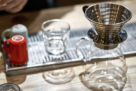 Empty kettle, glass, cups and coffee wave dripper on tableの写真素材