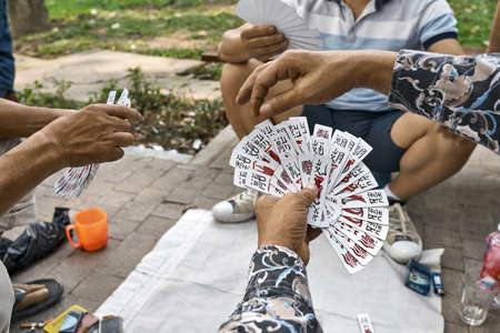 Asian gamers playing cards in park outdoorsの写真素材