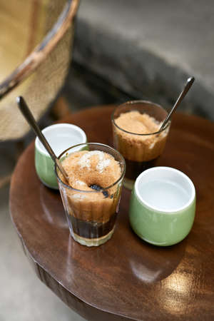 Refreshing iced coffee drinks and cups with water on round table outdoorsの写真素材