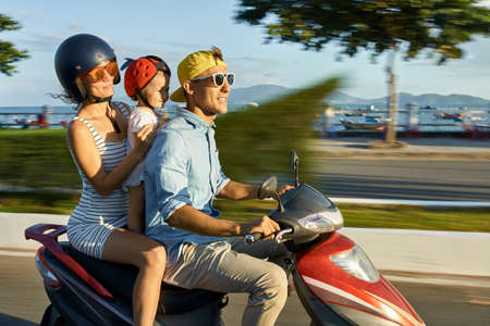 Parents with their child riding motorcycle on sunny city street