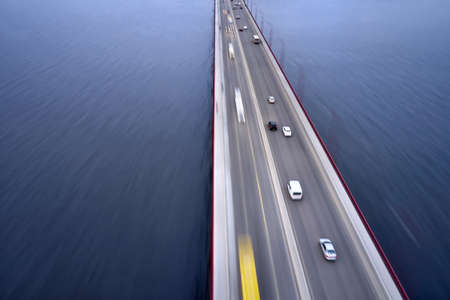 Wonderful bridge through Dnieper river with a traffic blurred in motion in city of Dnipro in Ukraine. It has red street lights and fencing. Aerial horizontal photo.の写真素材