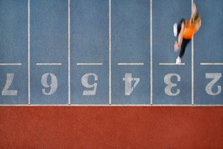 Athletic blonde woman running at colorful stadiumの写真素材