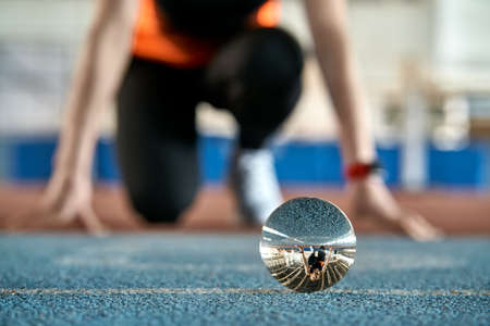 Reflection of sportive woman in glass ball during her running trainingの写真素材