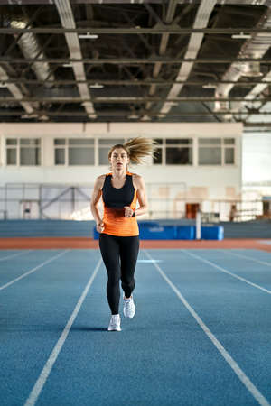 Sportive blonde woman training at indoor stadiumの写真素材