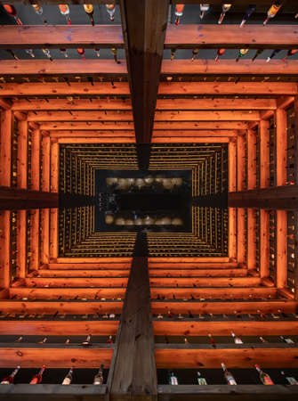Many wooden shelves with red backlight with alcohol drinks inside the restaurant. They reflected in...