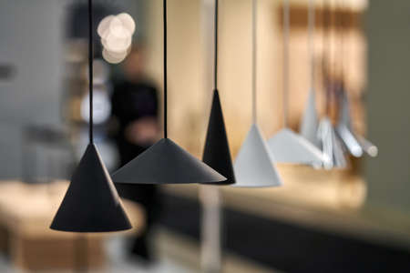 Row of different hanging metal black and white lamps on the blurred background of the illuminated...