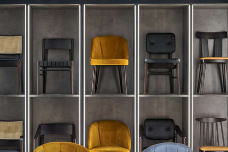 Multicolored different chairs are standing on the big shelves in the illuminated showroom. Horizontal.の写真素材