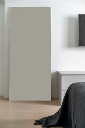 Beautiful modern bedroom with white walls and a parquet on the floor. There is a bed with a...
