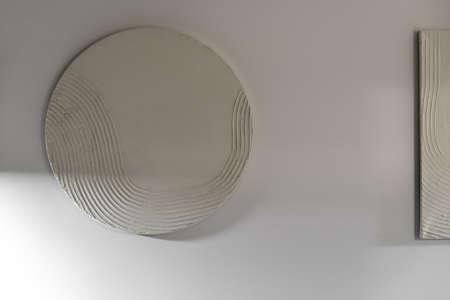 Light round and square relief pictures are hanging on the white wall in the luminous interior. Closeup. Horizontal.の写真素材