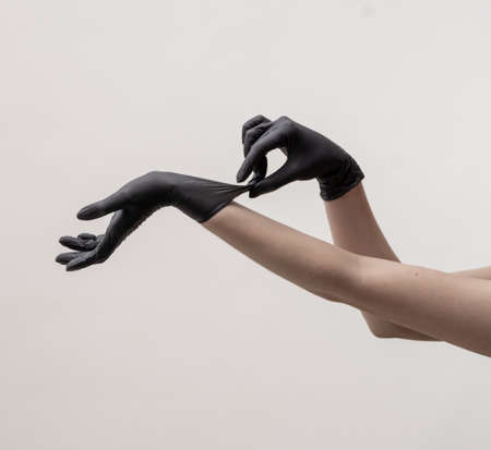 Hands in black silicone gloves on a light background.