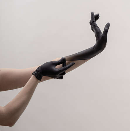 Hands in black silicone gloves on a light background.の写真素材
