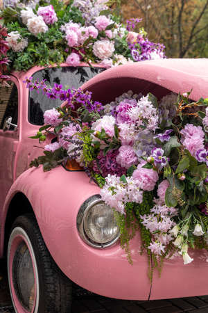 Vintage colorful auto loaded with flowers and transformed into decorationの写真素材