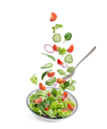 green salad falling into a plate on a white backgroundの写真素材