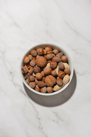 Different nuts in a white bowl on a gray tableの写真素材