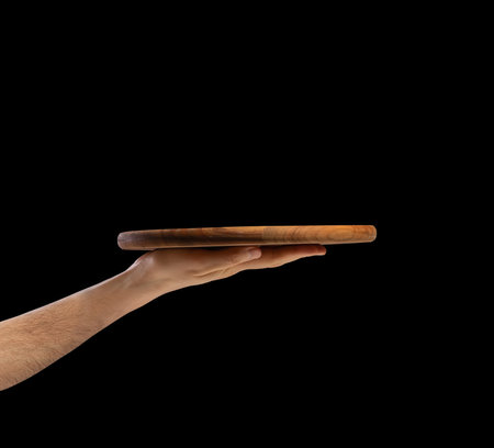 Man's hand with a round wooden board for making pizza or other food.の写真素材
