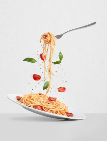 pasta with tomatoes and basil on a white background. Fork with pasta flying on a white background with tomatoesの写真素材