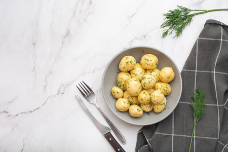 young boiled potatoes with butter and dill on a gray stone table.の写真素材